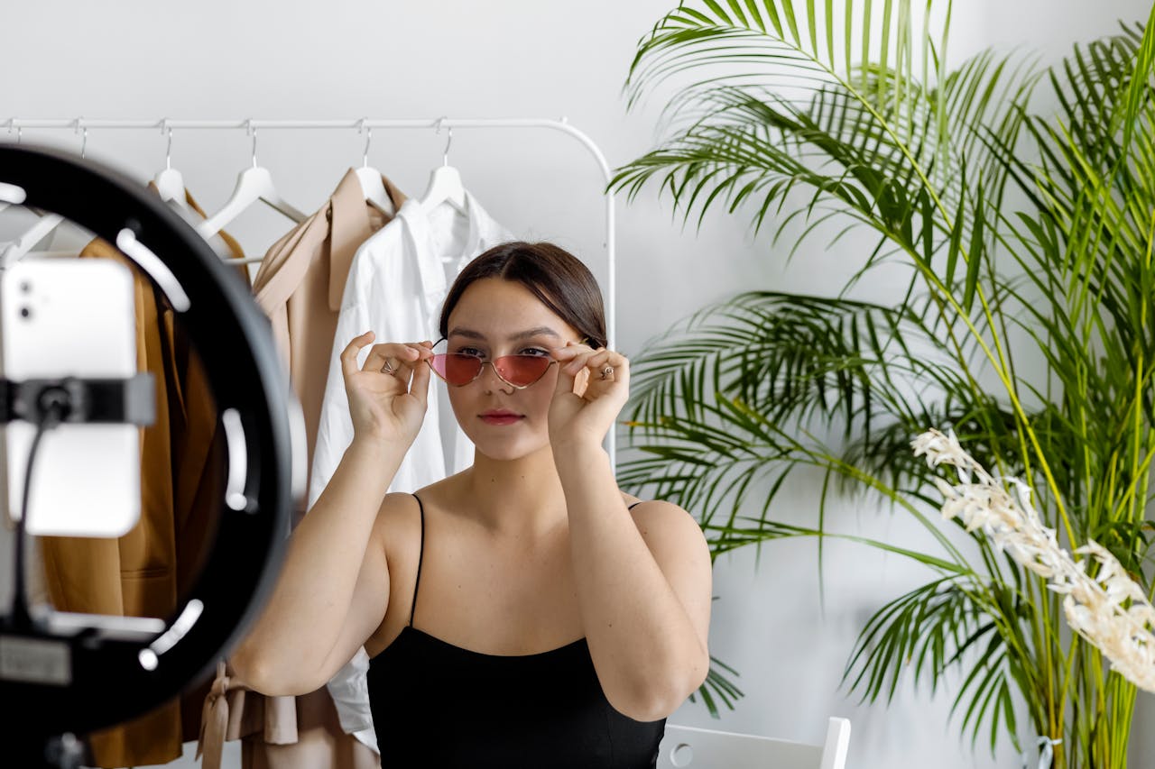 services-01 Stylish woman wearing sunglasses recording fashion content with a ring light indoors.