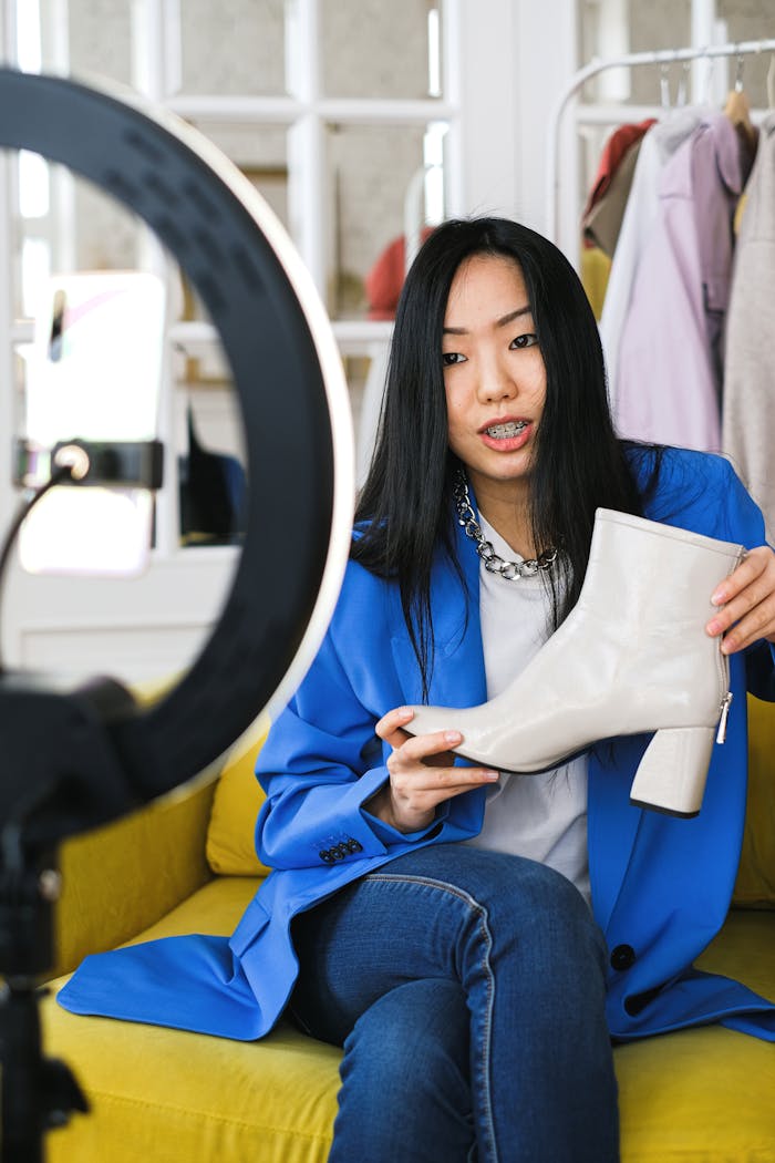 why-choose-us Young woman fashion vlogger recording a video about stylish white boots indoors.