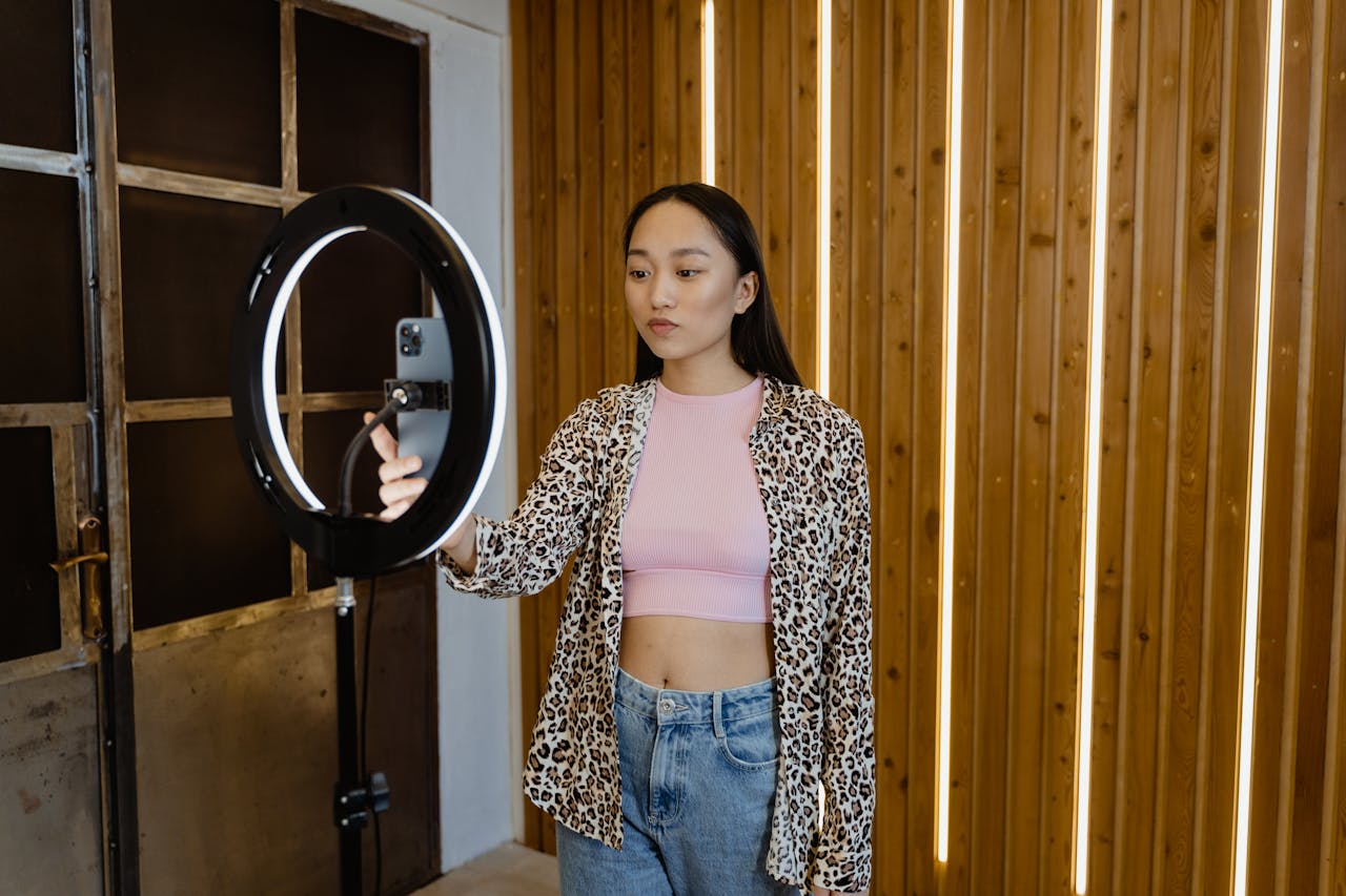 about-01 An asian woman influencer filming a vlog with a ring light in a stylish indoor setting.