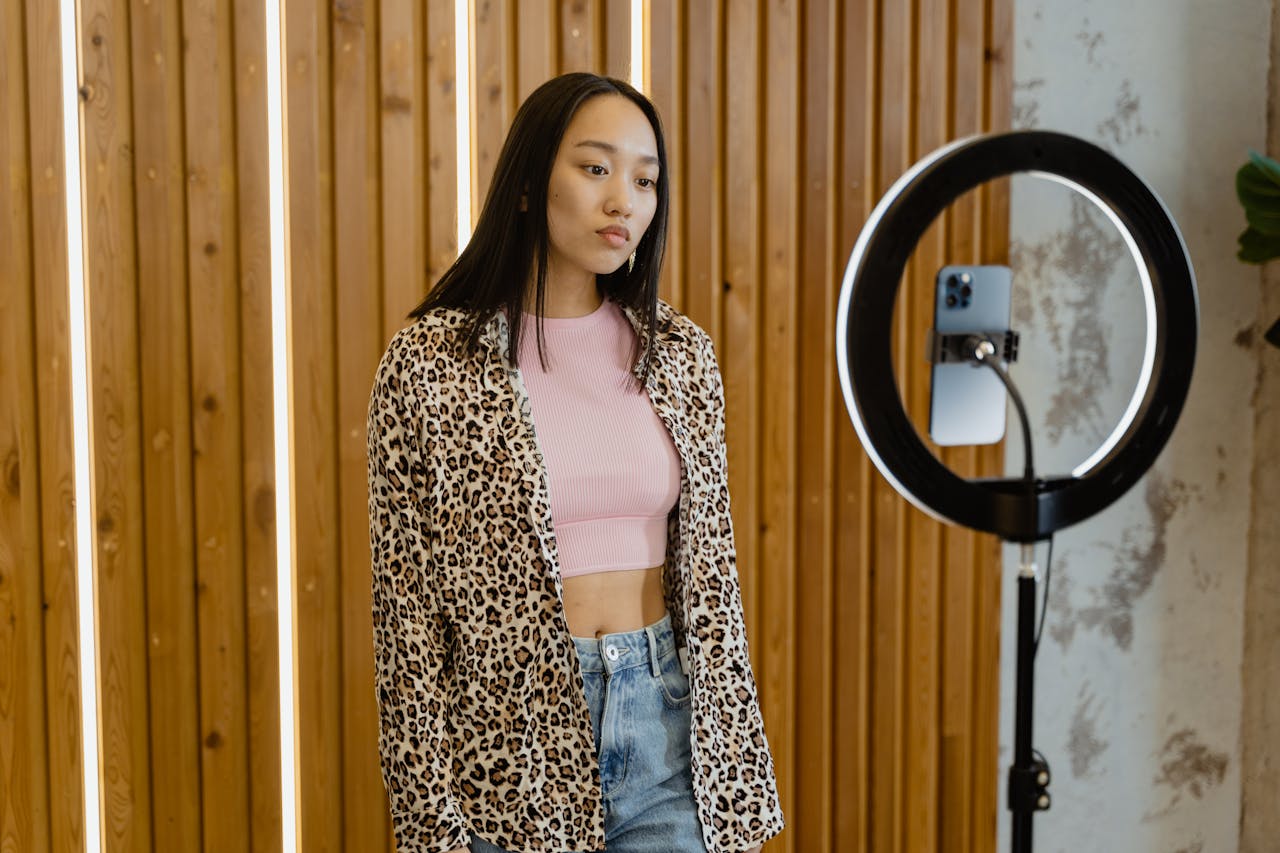 services-03 Asian female influencer recording content with ring light and smartphone indoors.