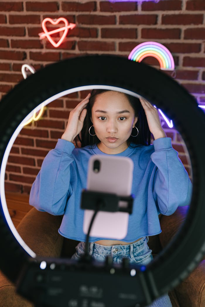 gallery-1 Asian woman recording a video with a smartphone and ring light for streaming purposes.