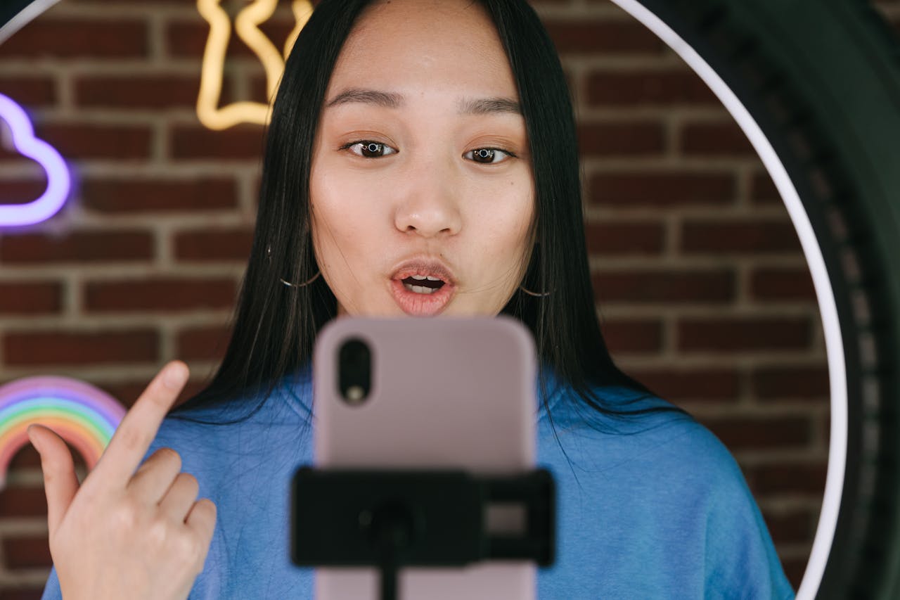services-02 Asian woman vlogging with smartphone and ring light, in a creative indoor setting.