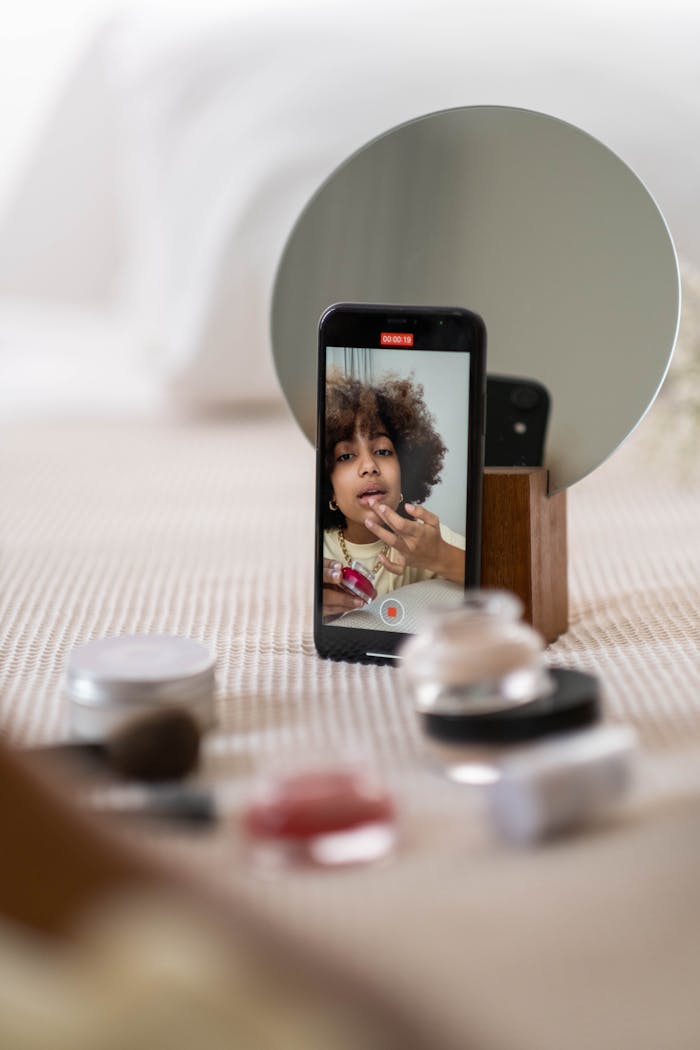 gallery-3 A beauty influencer vlogs a makeup tutorial using a smartphone indoors.